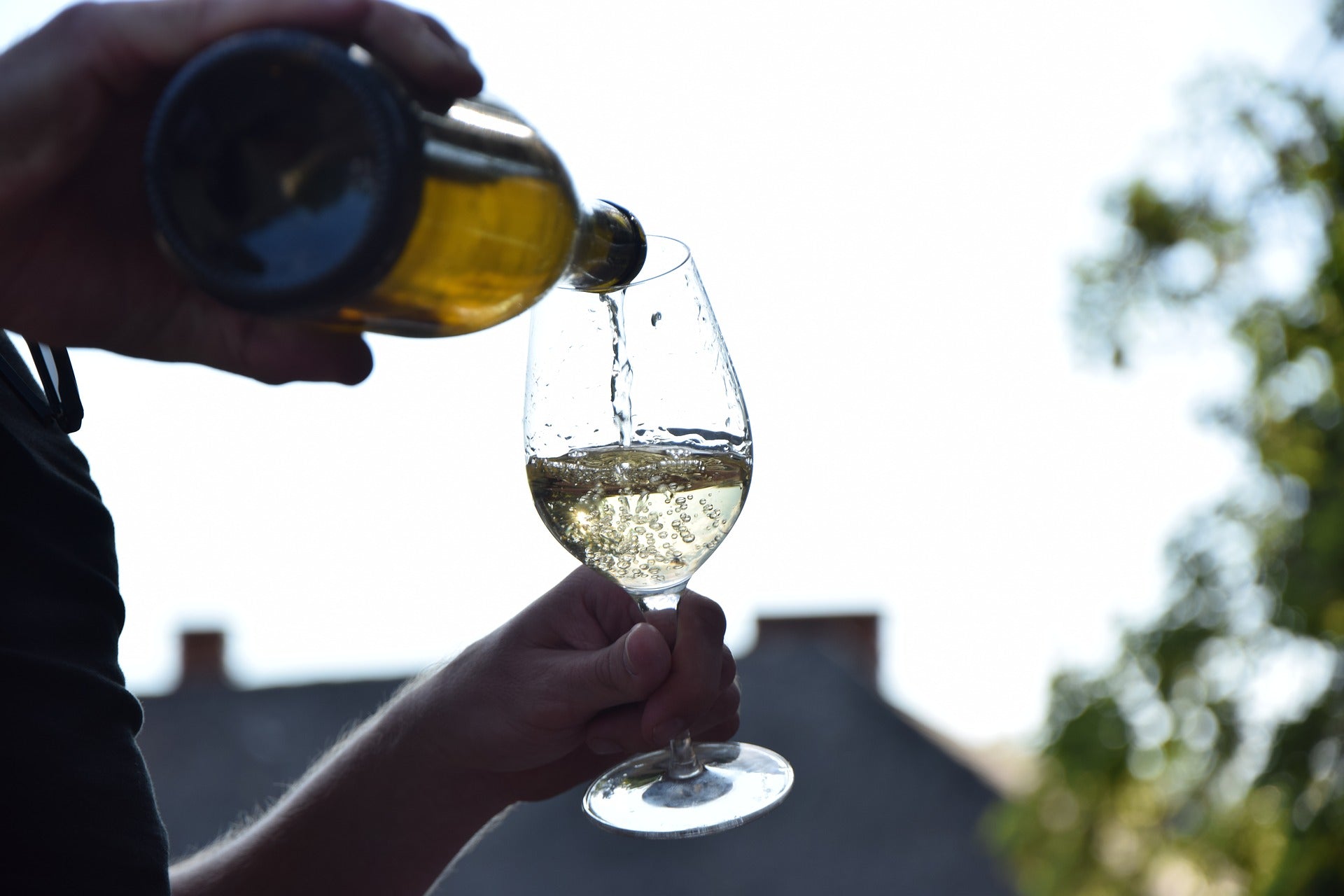 Ein Glas Wein steht auf einer am Boden liegenden Gitarre, die Weinflasche steht davor